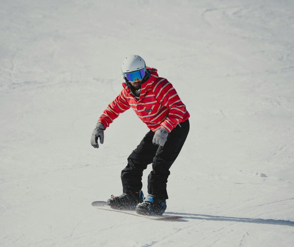 A snowboarder wearing a red jacket glides down a snowy slope, capturing winter adventure.