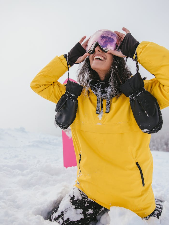 Woman in yellow jacket enjoying snowboarding adventure in winter.